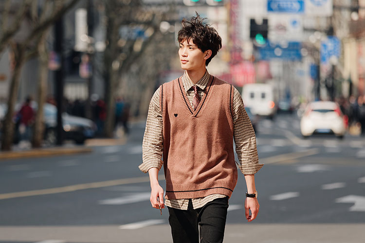 ブラウン系でまとめたおしゃれなファッションで歩く男性の写真