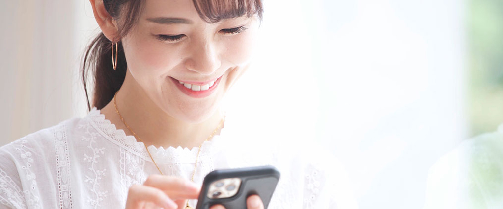 笑顔でスマートフォンを見ている女性の写真
