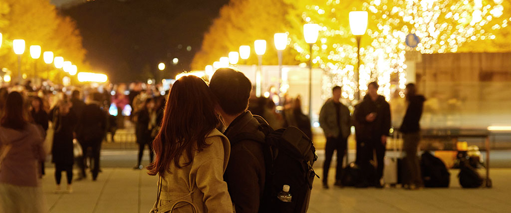 イルミネーションが輝く街を歩くカップルの写真