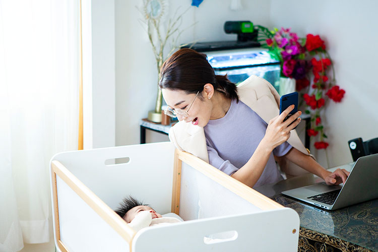 ベッドの赤ちゃんを覗き込む笑顔のお母さん