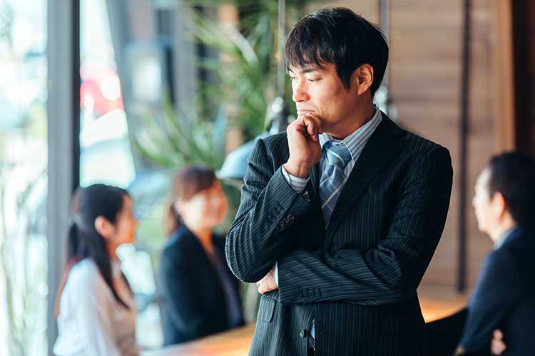 オフィスで考え事に耽る男性の写真