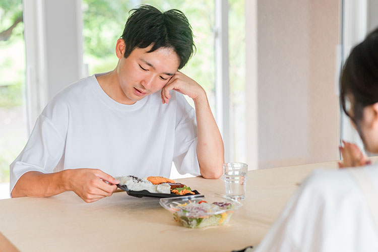 お弁当を前に不機嫌な男性の写真