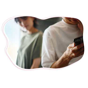 スマホをこっそり見る夫を怪しむ妻の写真